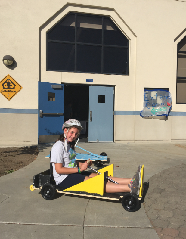 Emily Judith Mitnick presenting a cart in front of the summer camp entrance.