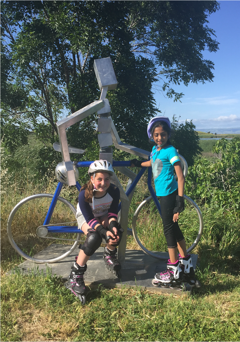 Emily Judith Mitnick on a rollerblade ride with a funny bike sculpture on a background.